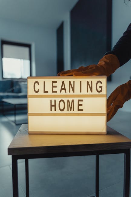 Three professional cleaning specialists from Dulwich Carpet Cleaners are performing a deep surface cleaning in a modern living room. The room features a sleek, dark wood accent wall behind the team, c